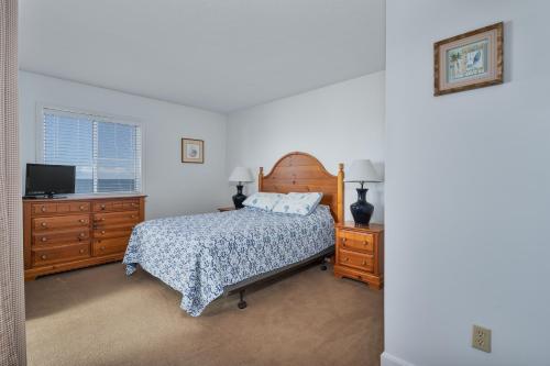 罗丹特7053 - Hatteras High 5C by Resort Realty的一间卧室配有一张床、两个梳妆台和一台电视。