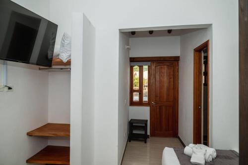 莱瓦镇HOTEL ALTIPLANO VILLA DE LEYVA的一间设有床铺、电视和门的房间