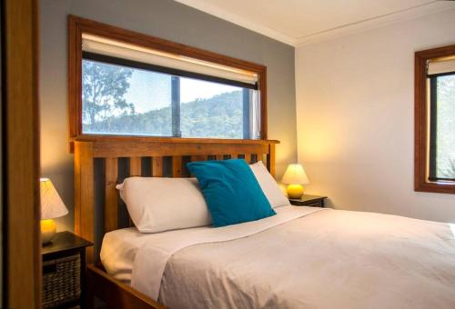 Alonnah布鲁尼岛休闲度假酒店的一间卧室配有一张带蓝色枕头的床和窗户