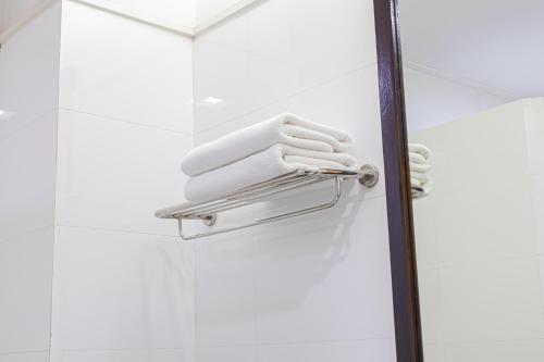 呵叻โรงแรม ซิตี้พาร์ค โคราช City Park Hotel的淋浴间的毛巾架和白色毛巾