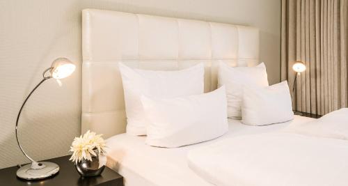萨尔布吕肯贝斯特韦斯特维克多罗登霍夫住宅酒店的一张白色的床,配有白色枕头和台灯