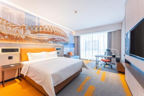 青山武汉高铁站希尔顿欢朋酒店的一间卧室配有一张床、一张书桌和一台电视。