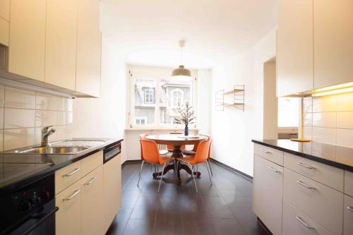 巴塞尔Modern 3-bedroom apartment in city centre的厨房配有桌子和橙色椅子