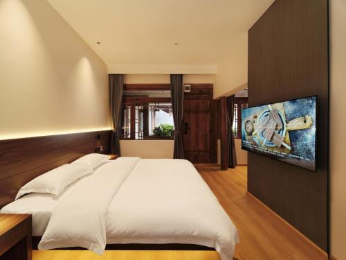 丽江夕露星期六智能度假花苑的卧室配有一张白色大床和一台平面电视。
