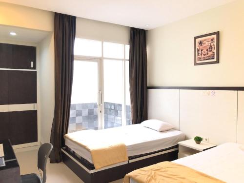 帕卢RedDooz Plus At Ininnawa Homestay Syariah Palu的酒店客房设有两张床和窗户。