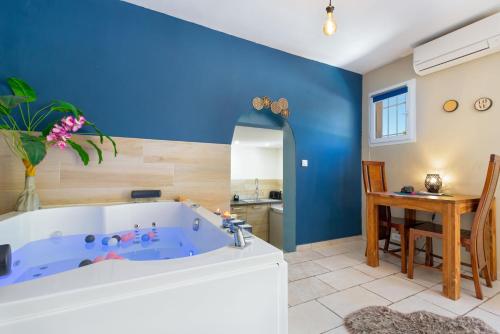 阿尔让河畔皮热Appartement jacuzzi 4 étoiles - Love Room Beauté的蓝色的浴室设有浴缸和桌子