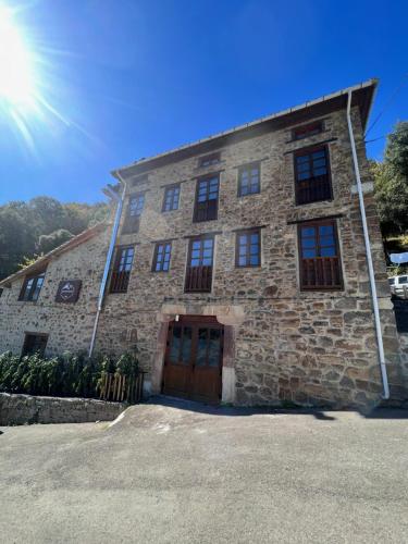 ArmañoCasa Rural Basiver - Habitación Pico Samelar的天空中阳光灿烂的石头建筑