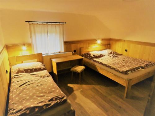 什平德莱鲁夫姆林Bouda Na Pláni - horská bouda的一间卧室设有两张床、一张桌子和一个窗口