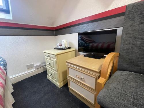 布莱克浦曼哈顿酒店的一间卧室配有一张床和一张书桌及电视