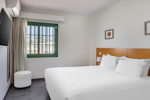 卡门港卡门俱乐部钻石度假村的卧室设有一张白色大床和一扇窗户。