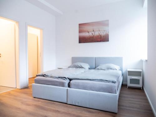 卡尔斯巴德Appartmenthaus Karlsbad的白色卧室配有一张床,墙上挂着一幅画