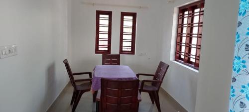 坎努尔Sivam Beach House的一间带桌椅和2扇窗户的用餐室