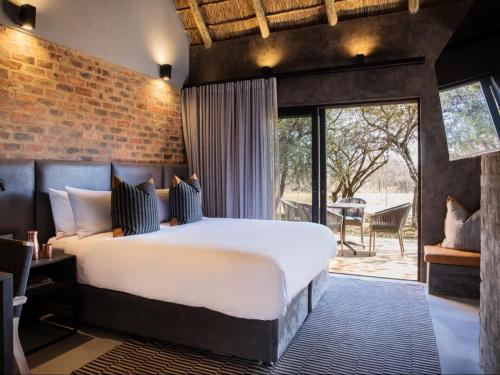 Dinokeng Game ReserveNAKO Safari Lodge的一间卧室设有一张大床和砖墙