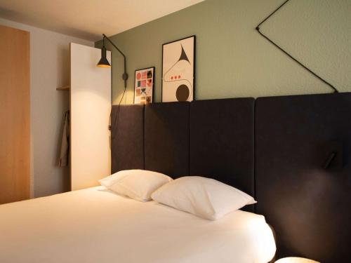 巴黎巴黎托尔比亚克宜必思酒店的一间卧室配有一张白色的床和黑色床头板