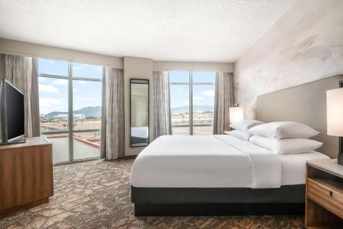 阿尔伯克基Embassy Suites by Hilton Albuquerque的酒店客房设有一张大床和一台电视。