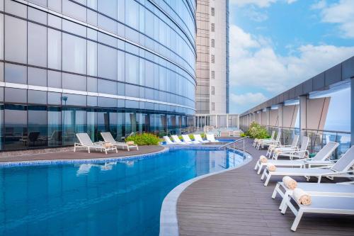 金沙萨Hilton Kinshasa的酒店游泳池设有躺椅,酒店大楼