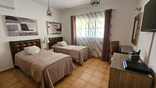 卡勒达德福斯特Villa BONITA on Golf in El Descanso ,Caleta Fuste-Fuerteventura的酒店客房设有两张床和窗户。