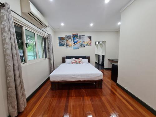 苏瓦Nasese paradise的一间卧室配有一张铺有木地板的床和窗户。