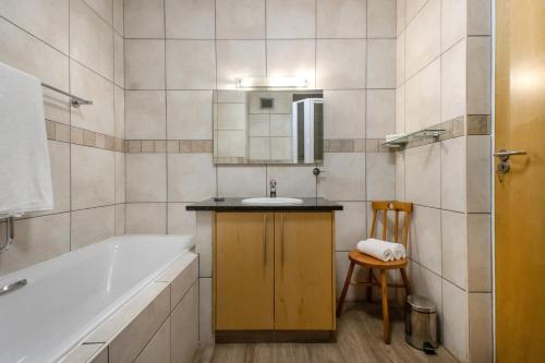 开普敦Hibernian Towers 309 Strand - Luxury Self Catering的带浴缸、水槽和椅子的浴室