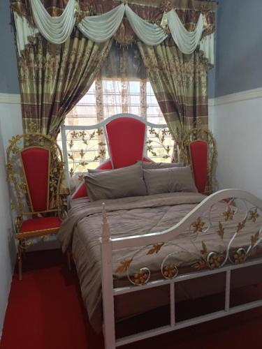 小笨珍Homestay ALHAQIM的卧室配有一张床和两把椅子,位于窗户前