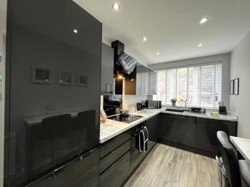 曼彻斯特Modern 3-bed stay-away-home sleeps 6 nr Manchester的大型厨房设有黑色橱柜和大窗户