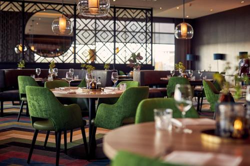 吕伐登Van der Valk Hotel Leeuwarden的餐厅设有木桌和绿色椅子