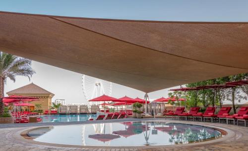 迪拜安瓦吉罗塔纳朱梅拉海滩酒店-迪拜的一个带红色椅子和红色遮阳伞的大型游泳池