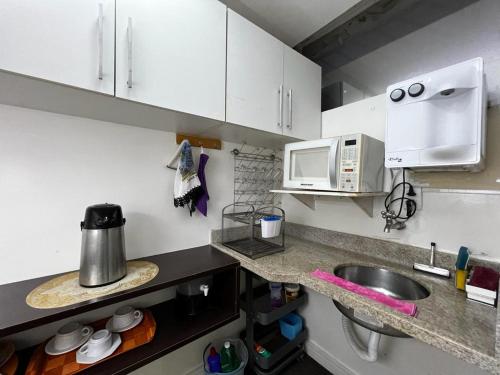 巴西利亚Hospedagem BRASILIANAS的厨房配有白色橱柜、水槽和微波炉