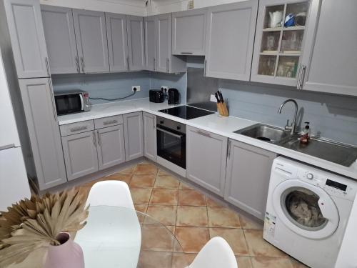 布罗姆利What a great location in Bromley with 4 bedrooms!的厨房配有白色橱柜和洗衣机。