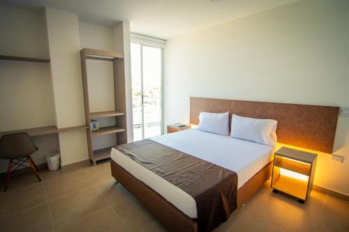阿卡西亚斯HOTEL EL NARANJO的一间卧室设有一张大床和一个窗户。