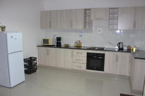 卢萨卡Busisiwe's RM Home的厨房配有木制橱柜和白色冰箱。