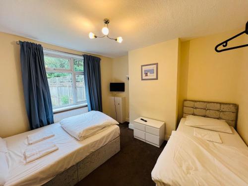 伦敦Three Bedroom House with private car park的一间卧室设有两张床和窗户。