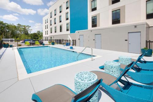 比洛克西Hampton Inn & Suites D'Iberville Biloxi的一个带桌椅的游泳池和一个游泳池