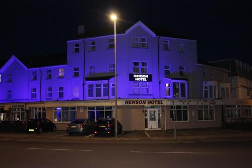 布莱克浦游乐海滩亨森酒店的一座紫色的建筑,前面有汽车停放