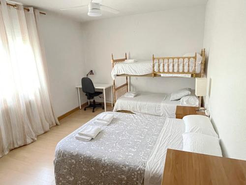 纳瓦尔卡内罗Villa Flores的一间卧室配有两张床和一张带电脑的书桌