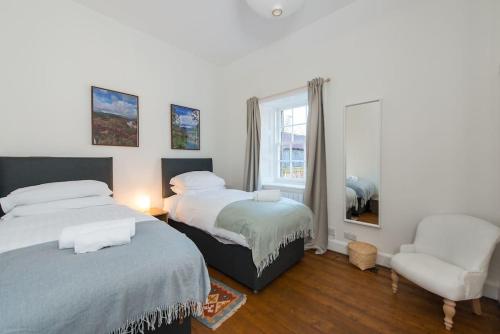 北贝里克Stunning Stables Cottage in East Lothian Country Estate的一间卧室设有两张床、一把椅子和一个窗户。