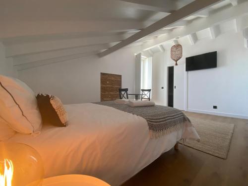 格兰杜拉Grândola Suites - Suite Loft的一间卧室配有一张大床和电视