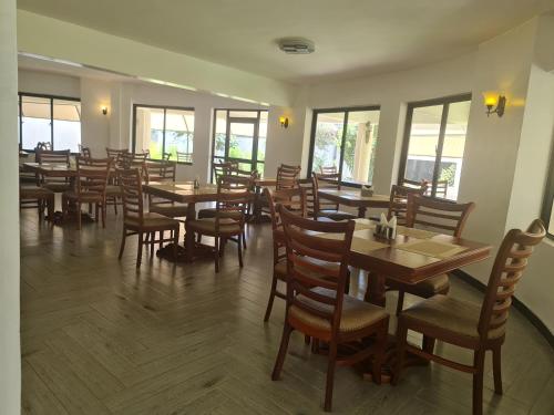纳库鲁Ol Muteita Lodge的餐厅设有木桌、椅子和窗户。