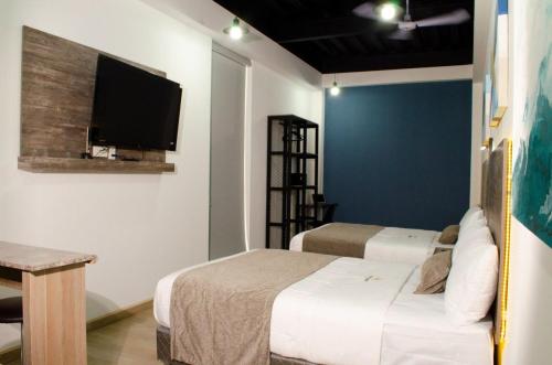 恩塞纳达港Hotel StayHome的一间卧室设有两张床,墙上配有电视。