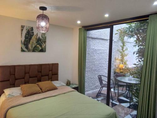 安巴托Jardines Ambato的一间卧室配有一张床、一张桌子和一个窗户。