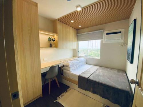 伊洛伊洛Riverview Two Bedroom Condo at One Spatial Iloilo的一间卧室配有一张床、一张书桌和一个窗户。