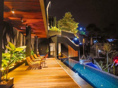 沃诺索博Hotel Dafam Wonosobo的一个带椅子的木甲板和夜间游泳池