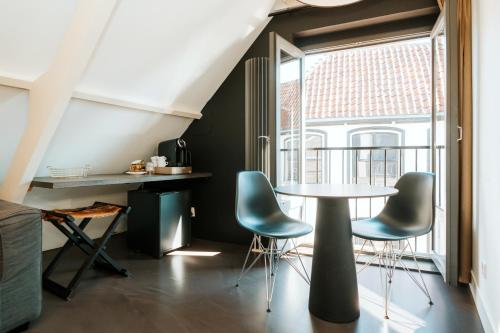 登堡Texels Goud Deluxe Suites的客房设有桌椅和窗户。
