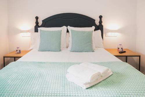 阿尔苏阿Apartamentos Luis的一张带绿毯的床和两个枕头
