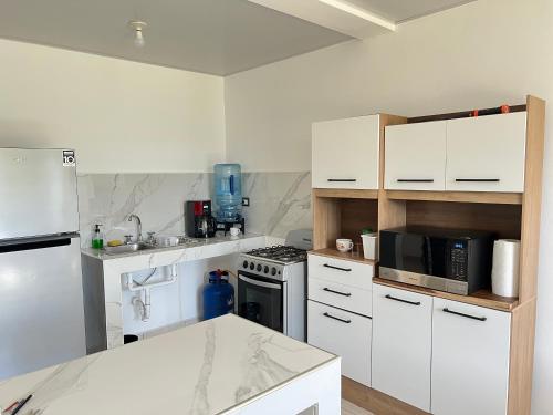 松索纳特Comfortable and roomy, in Sonsonate的厨房配有白色橱柜和炉灶烤箱。