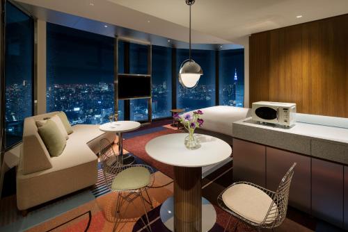东京HOTEL GROOVE SHINJUKU, A PARKROYAL Hotel的酒店客房配有床、沙发和桌子。