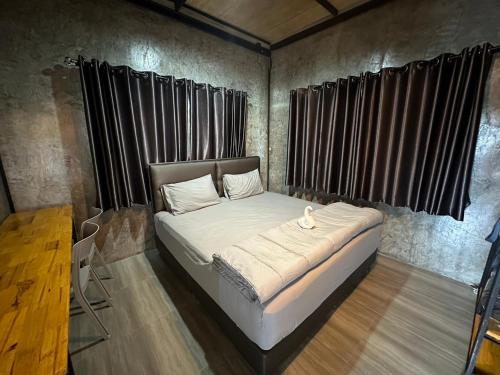 暖武里府The Nack Resort & Pool Villa บางบัวทอง的一张位于带黑色窗帘的房间的床铺