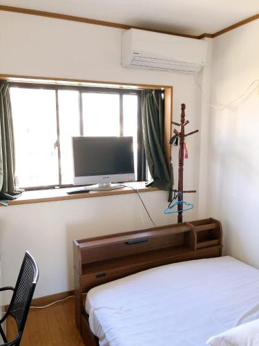 大阪HOSTEL198 Private Room of Third floorーVacation STAY68050v的一间卧室设有一张床、一台电视和一个窗口。