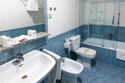 桑坦德圣格洛里奥酒店的浴室配有盥洗盆、卫生间和浴缸。