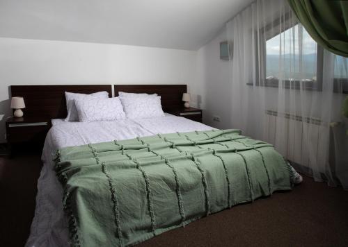 拉兹洛格Pirin Bliss Apartment Ski, Spa and Relax at Terra Complex的一间卧室配有一张带绿色棉被的大床